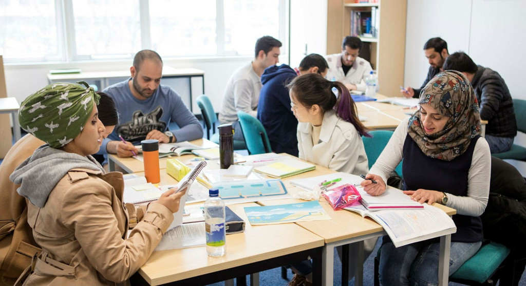 Photograph of people gathered around tables in a community discussion setting, sharing information and exploring practical solutions to financial challenges, community support and improving wellbeing