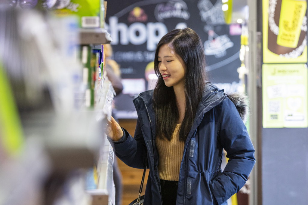 Photograph of a young person browsing products in a shop, highlighting everyday choices about spending, budgeting, education and future financial decision-making.