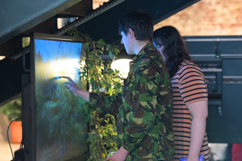 People taking part in an interactive digital activity on a large touchscreen display, exploring decision making, risk, and the factors that influence choices.