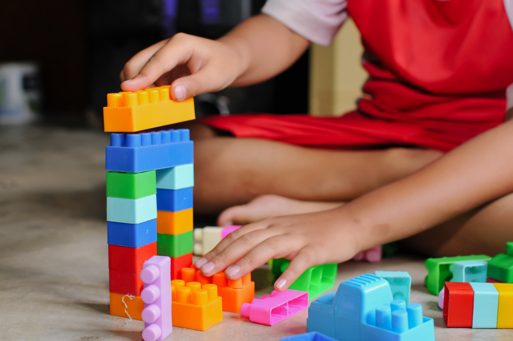 The picture shows a child playing with colourful building blocks.