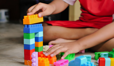 The picture shows a child playing with colourful building blocks.