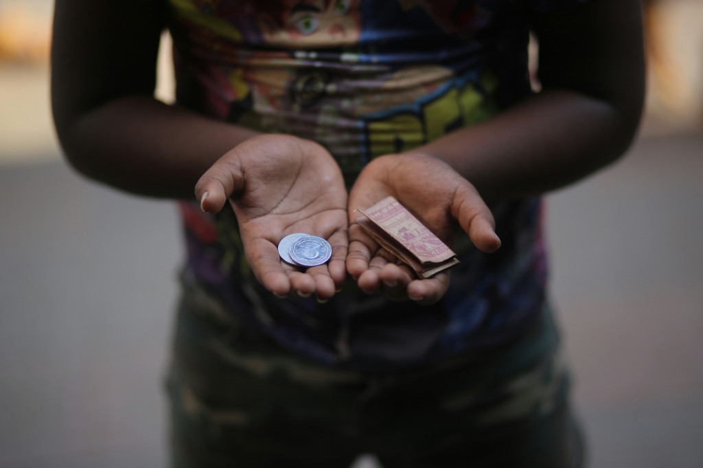 A child holding coins and a bank note.