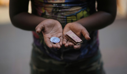 A child holding coins and a bank note.
