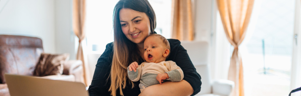 Mother holding baby whilst working