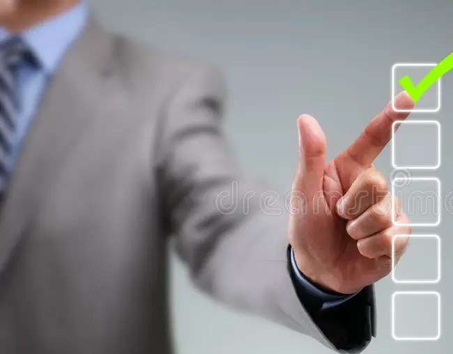 A formally dressed man wearing a suit and tie is selecting a tick box with his hand.