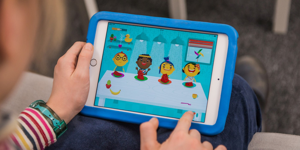 A child is playing an iPad game, sharing food between characters.
